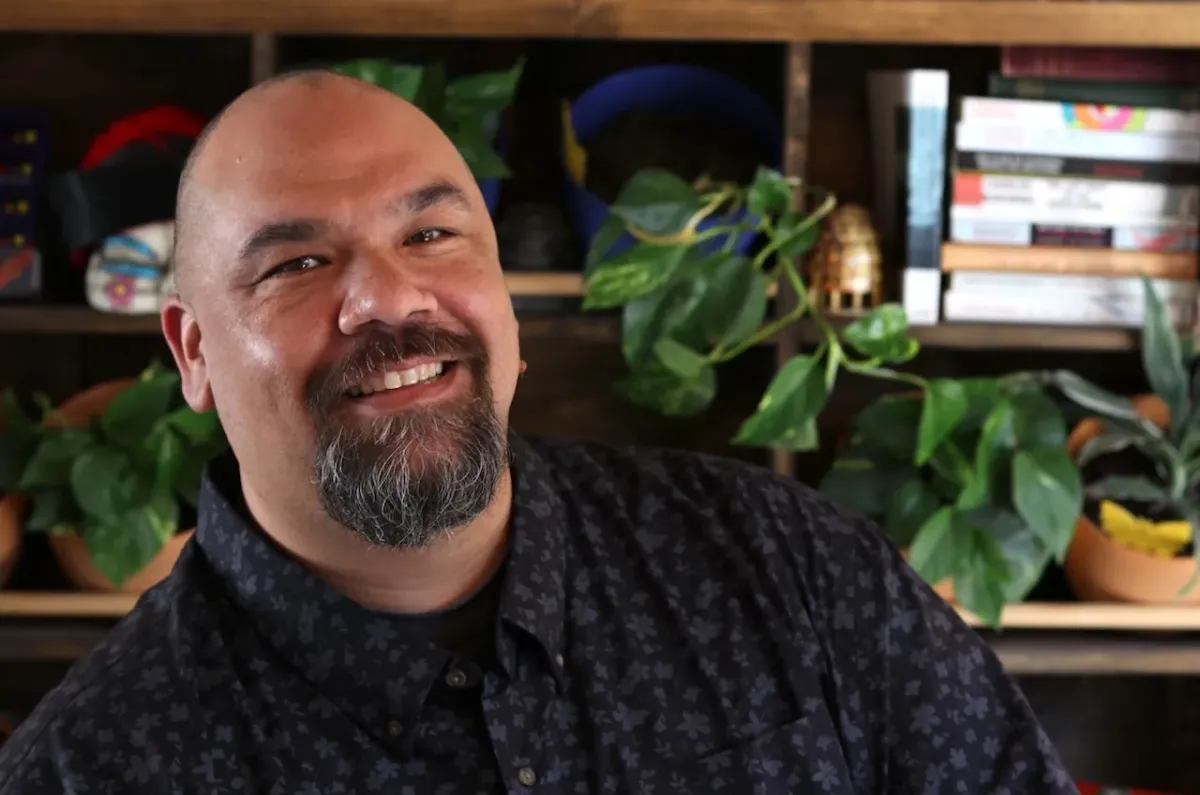 A brightly smiling man with a striking van-dyke beard, looking directy at the viewer.