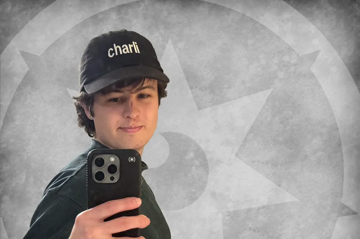 The author is smiling into a phone camera, taking a selfie, wearing a baseball cap that says, "charli,"