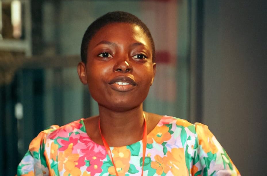 A smiling young woman wearing a colorful floral dress.