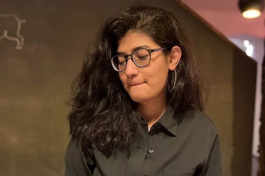 A picture of Shivani in a green shirt-jacket getting ready to devour a plate of food.