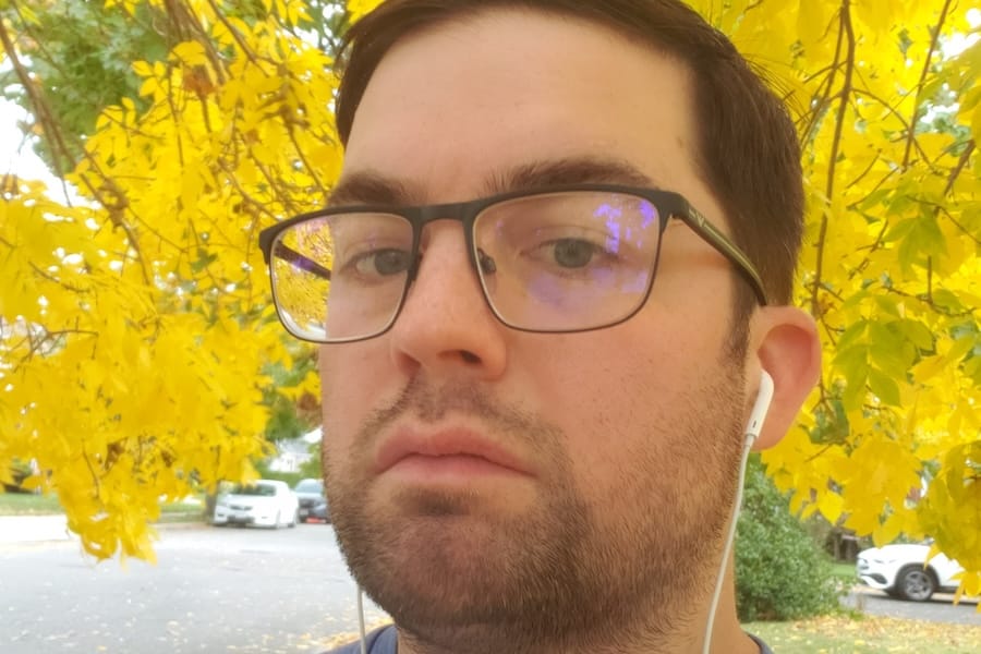 Alex J. Tunney with his head framed by the yellow leaves of a tree.
